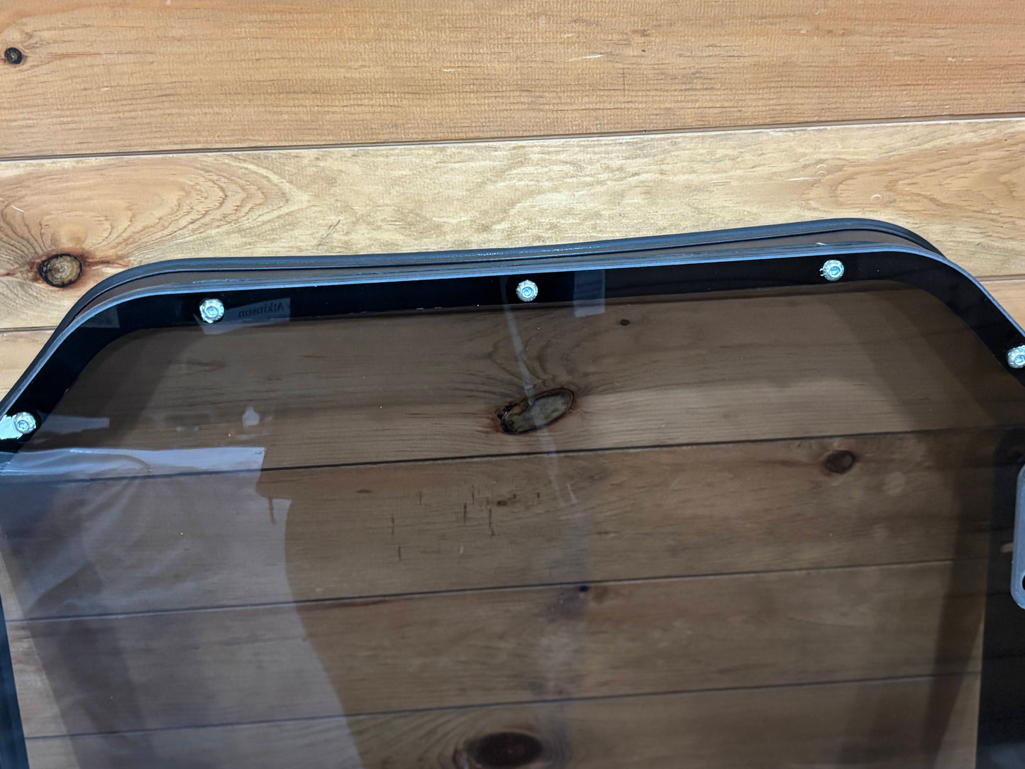 Bobcat R Series door frame top rail overhead close-up showing curved top section with teal mounting hardware bolts