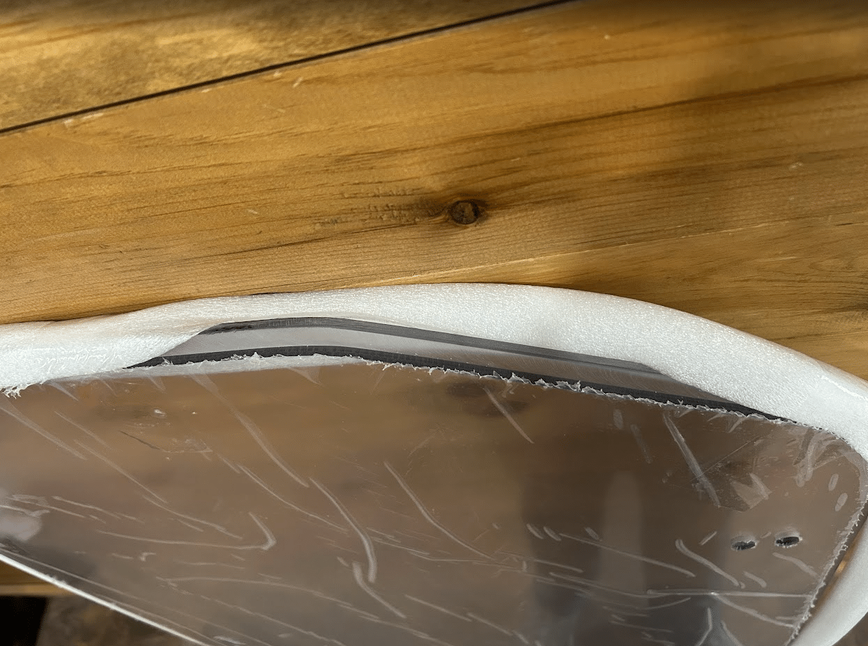 Close-up of ASV Max-Series windshield top edge showing polycarbonate panel thickness, foam gasket seal, and rubber edge trim