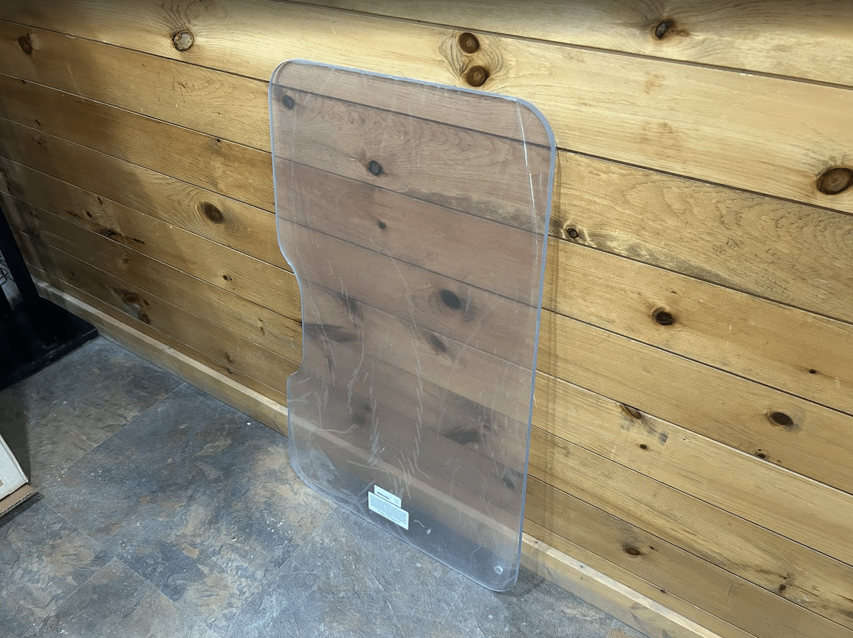 ASV PosiTrack RC85 RC100 polycarbonate windshield leaning against wall showing side view and stepped bottom profile
