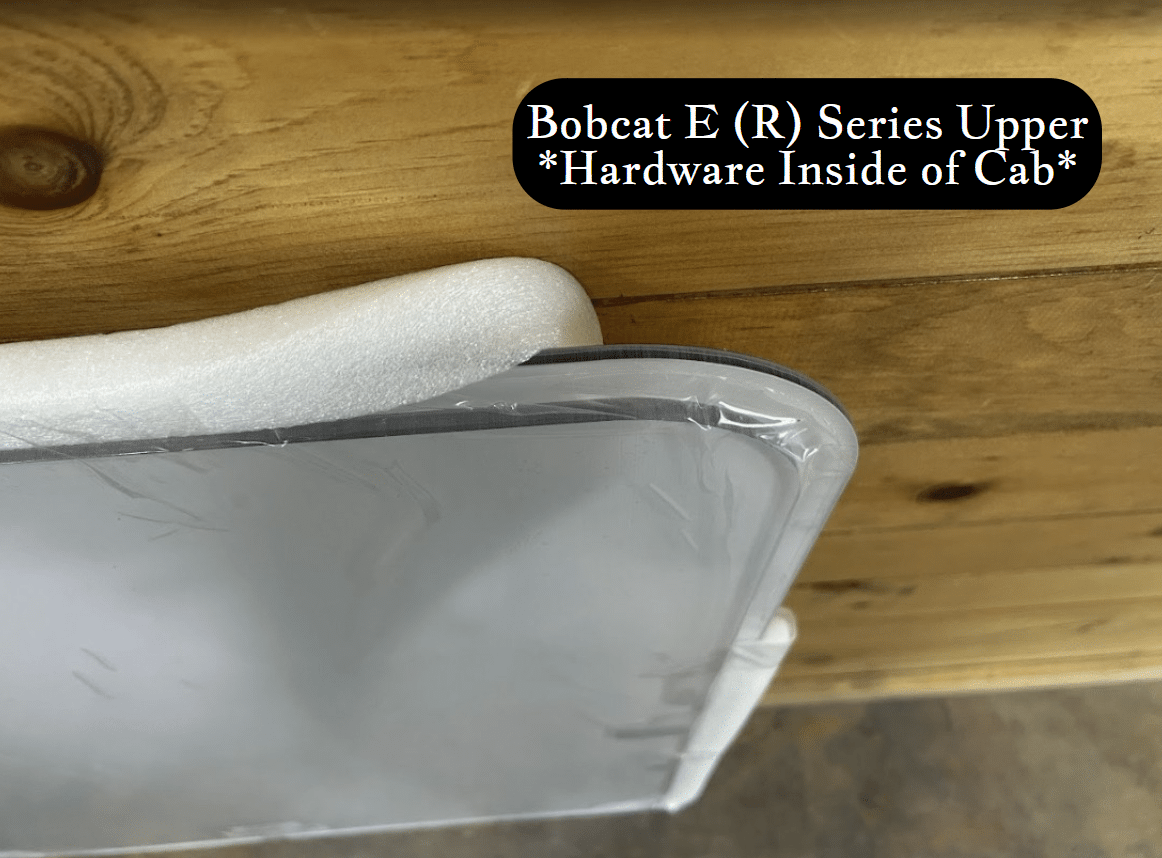 Top arc edge detail of Bobcat E (R) Series upper windshield showing curved foam seal and polycarbonate panel thickness