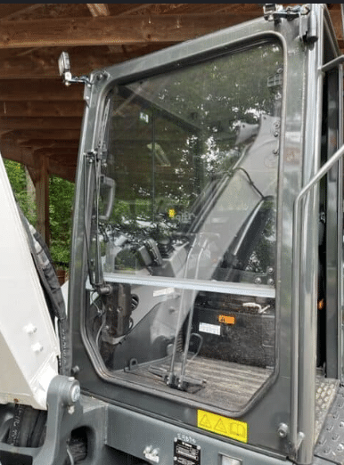 Bobcat excavator cab with clear polycarbonate windshield installed, viewed from outside showing full front window panel