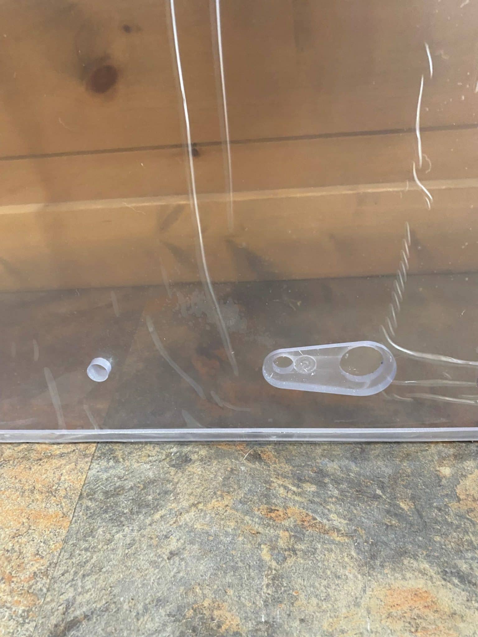 Bottom edge of Bobcat G Series polycarbonate windshield replacement showing wiper mount bracket and mounting stud detail