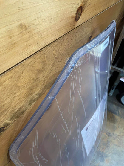 Side edge view of Bobcat G Series clear polycarbonate windshield replacement in protective wrap, showing panel thickness and edge profile