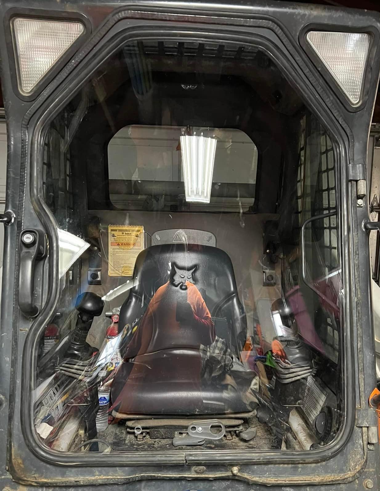 Interior view of a Bobcat G Series skid steer cab with door open, showing operator seat and controls where windshield mounts