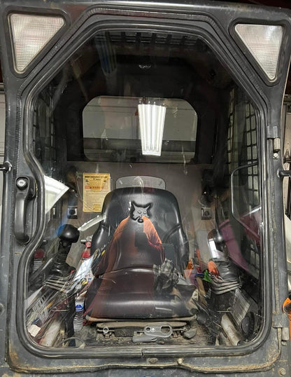 Interior view of a Bobcat G Series skid steer cab with door open, showing operator seat and controls where windshield mounts