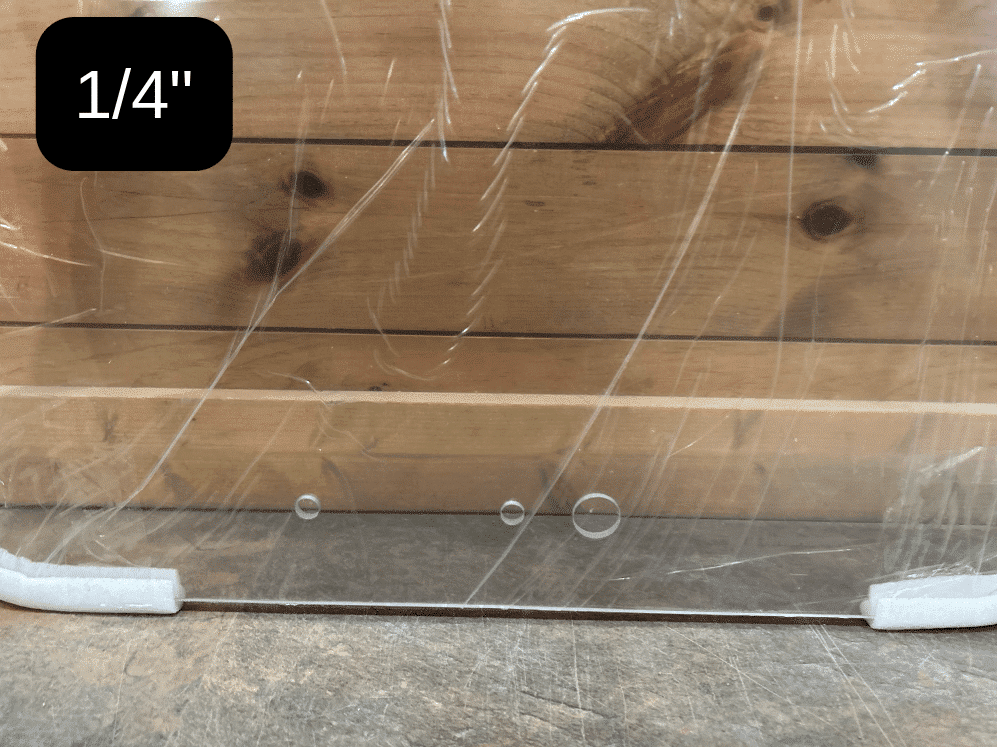 Bottom edge of Bobcat G Series 1/4 inch polycarbonate windshield in protective wrap with foam corner protectors, labeled 1/4 inch thickness