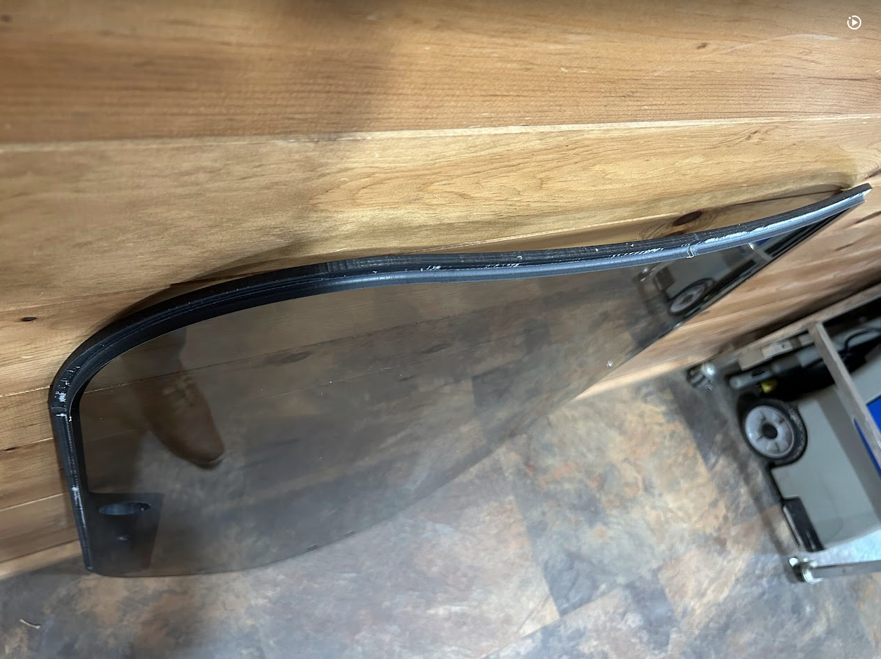 Close-up of black rubber door seal corner detail on Bobcat M Series 2-hole forestry windshield, showing flexible gasket edge wrap