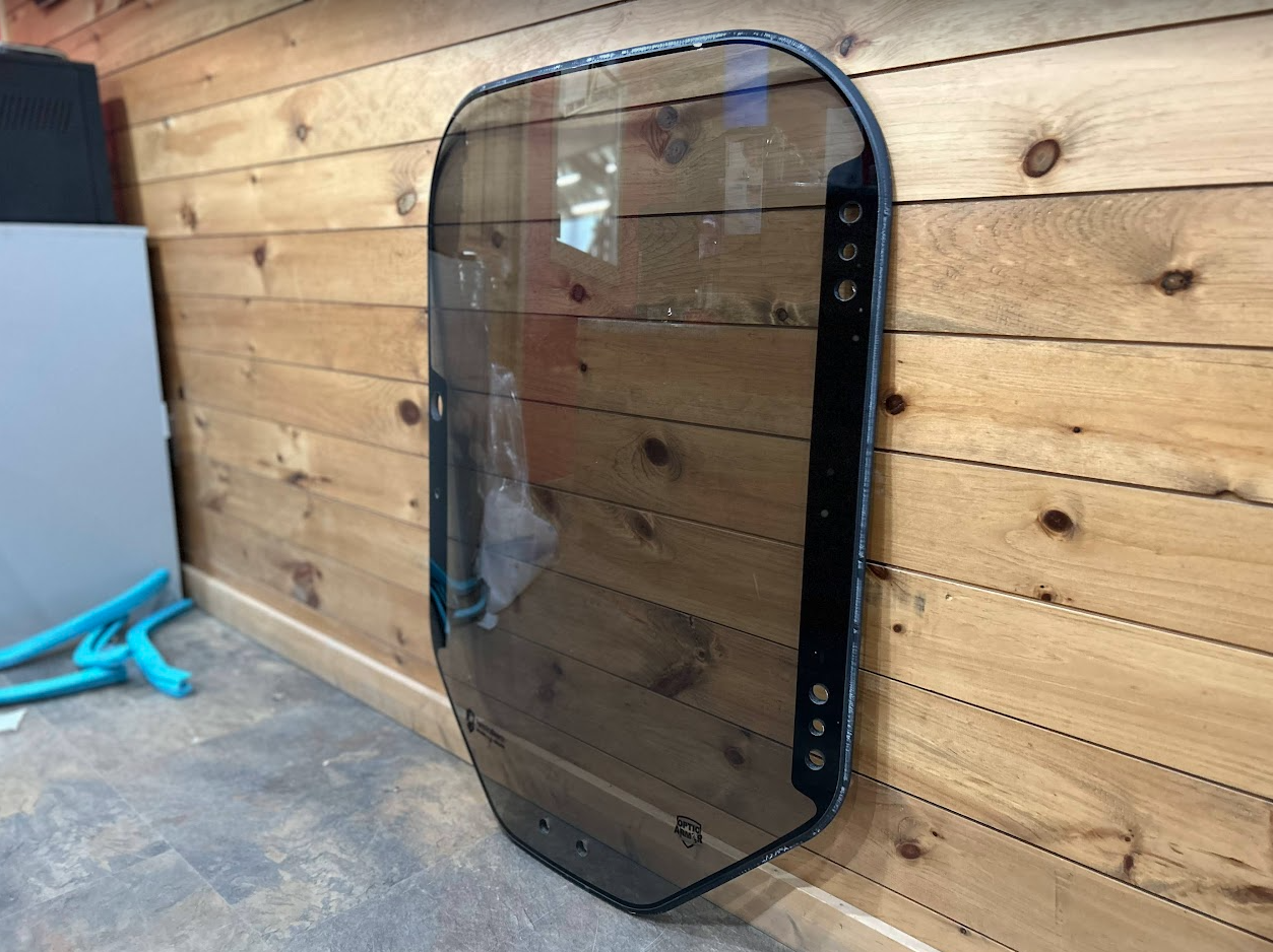 Bobcat M Series 2-hole forestry windshield with black door seal frame, right side view showing mounting studs along the edge