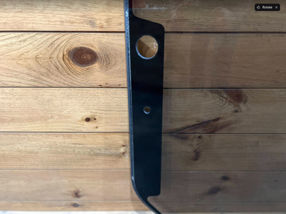 Close-up of Bobcat M Series 2-hole forestry windshield frame left hinge side showing round mounting hole in black steel frame