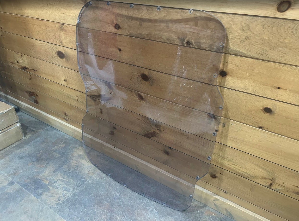 Bobcat M Series 3/4 laminated polycarbonate forestry windshield showing full shape with curved side cutouts and mounting hardware