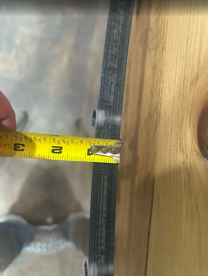 Close-up of Bobcat M Series forestry windshield edge with measuring tape showing 3/4 inch laminated polycarbonate thickness