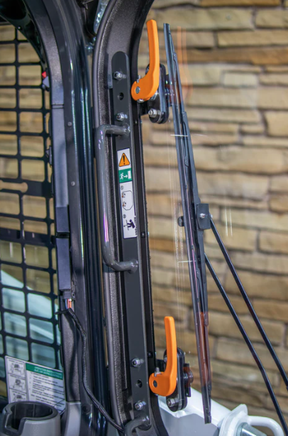 Interior view of Bobcat M Series forestry door showing wiper arm, orange quick-release latch handles, and mesh guard