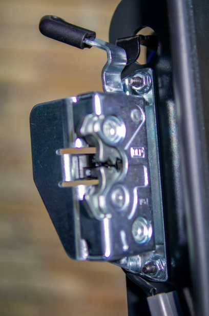 Close-up of Bobcat M Series forestry door OEM latch mechanism with handle plunger and striker assembly