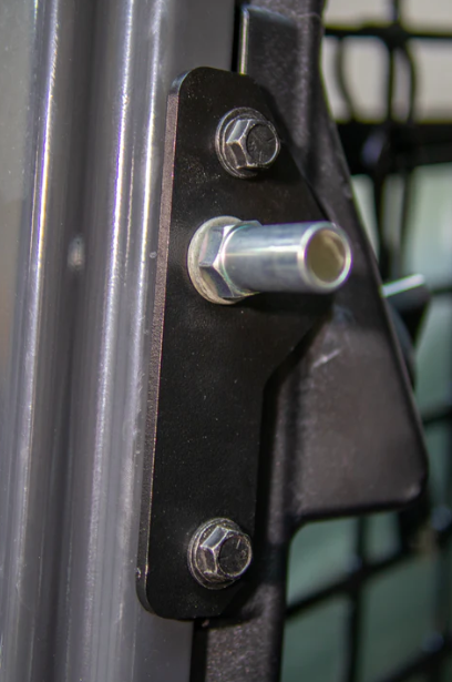 Close-up of Bobcat M Series forestry door striker bracket mounted to door frame with bolts and mesh guard