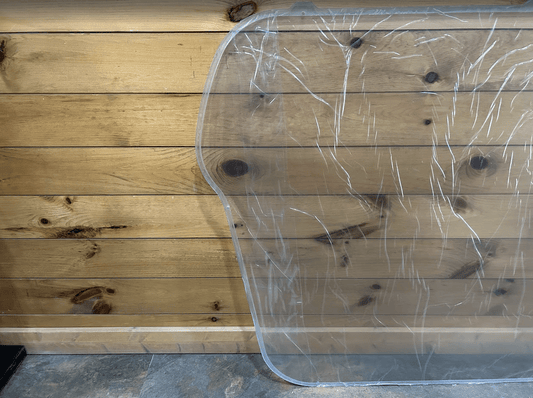 Bobcat M Series polycarbonate side window showing back side with protective film, curved profile and cutout visible