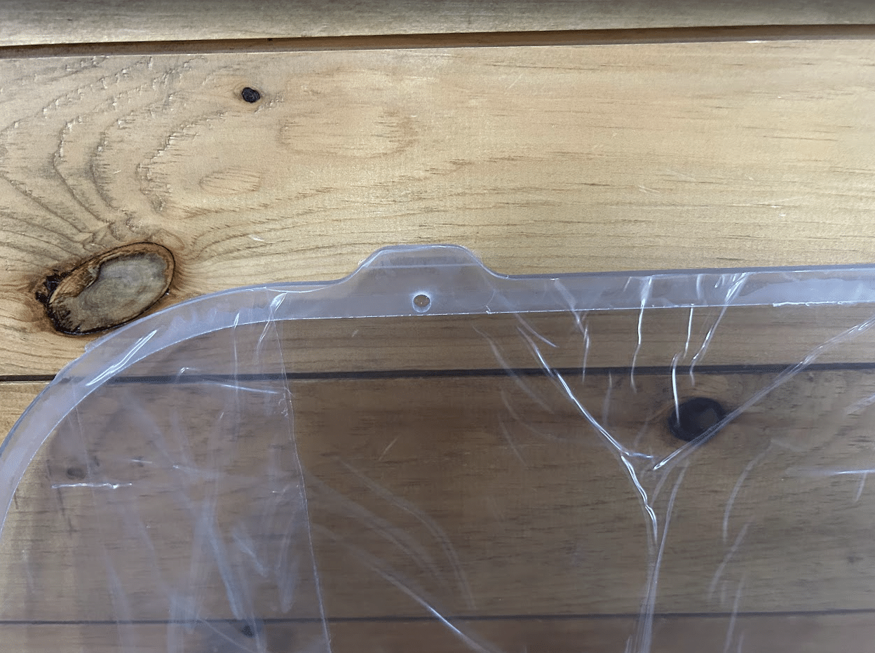 Close-up of Bobcat M Series polycarbonate side window top edge showing rubber seal channel and mounting post