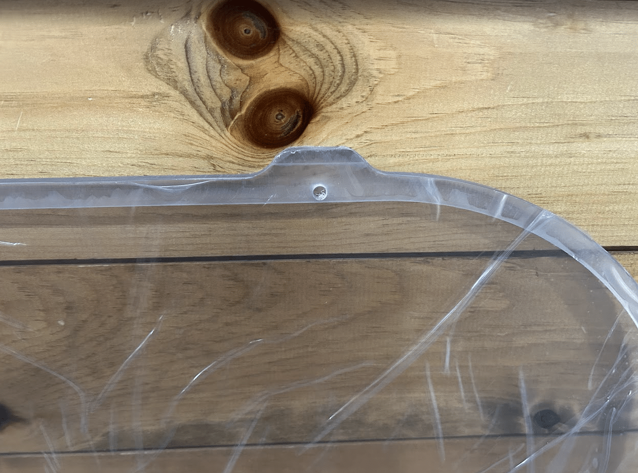 Close-up of Bobcat M Series polycarbonate side window upper corner showing rubber seal gasket channel and curved edge