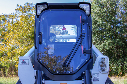 Bobcat M Series skid steer with forestry door and polycarbonate windshield installed, front view with wiper
