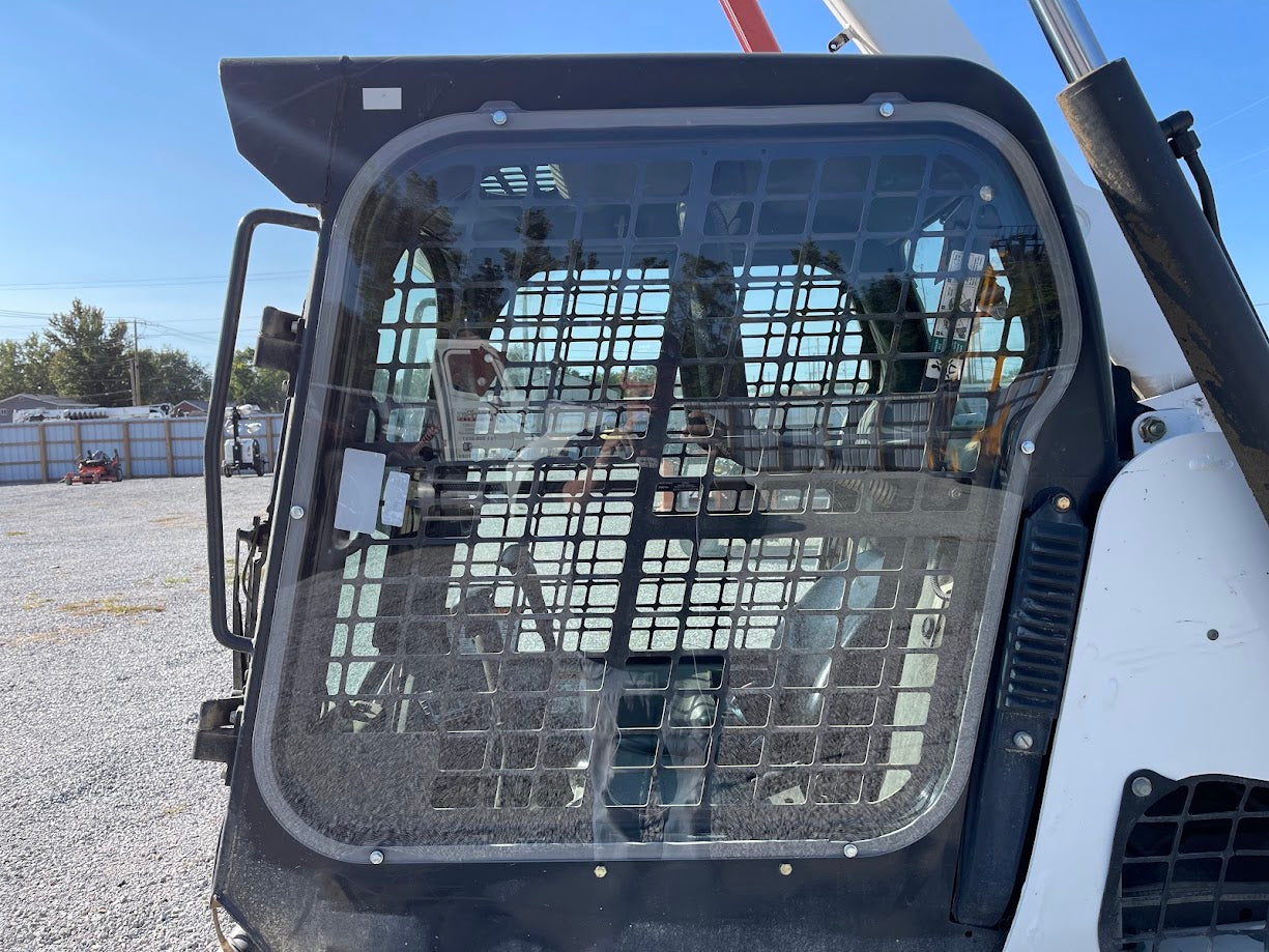 Bobcat M Series skid steer full side cab view showing polycarbonate side window installed with mesh guard, outdoor setting