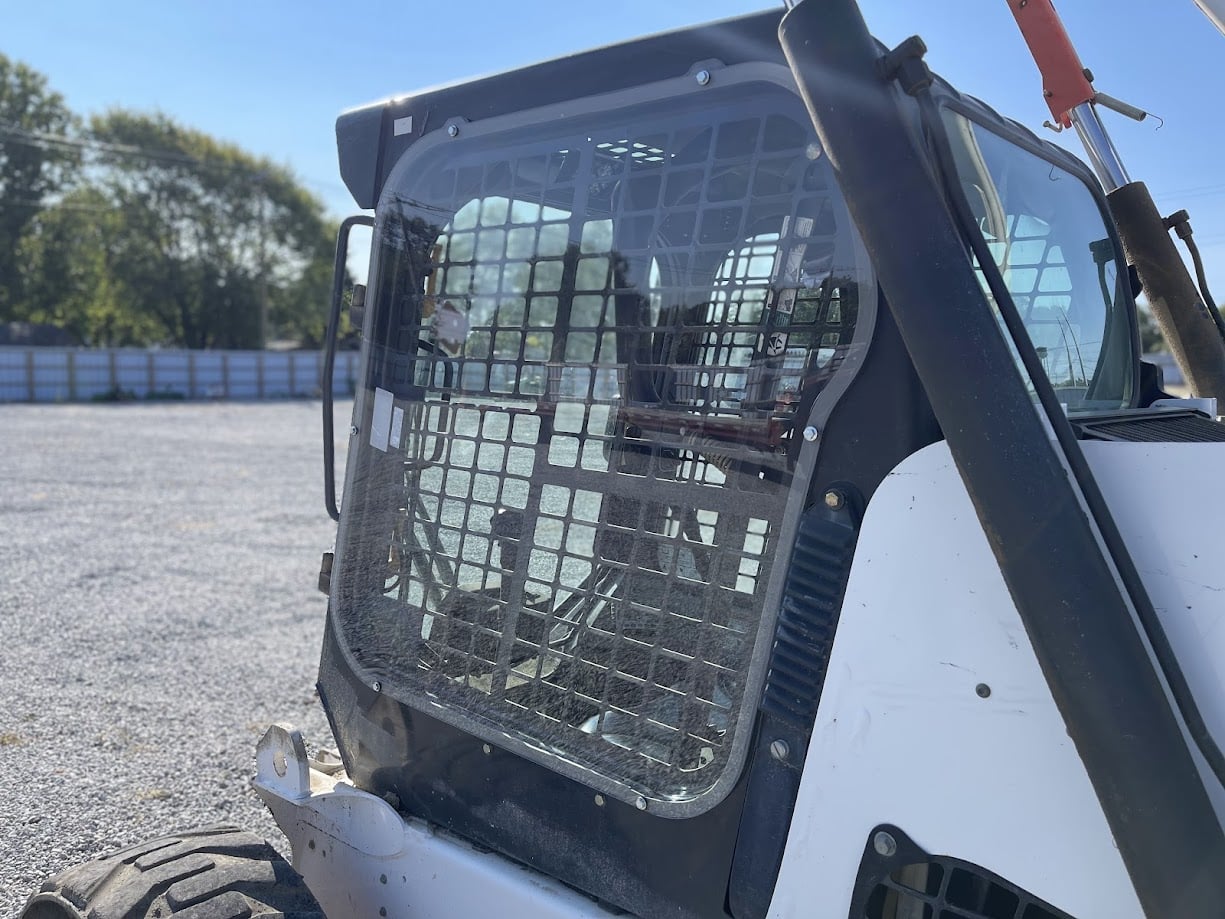 Bobcat M Series skid steer side cab view showing door, mesh guard, and OEM side window frame location