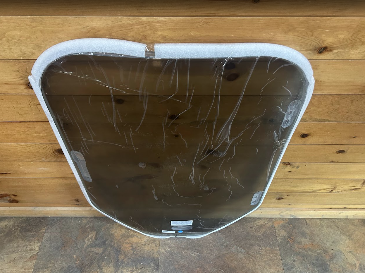 Bobcat M Series tinted polycarbonate windshield, elevated front view showing white perimeter seal and latch hardware