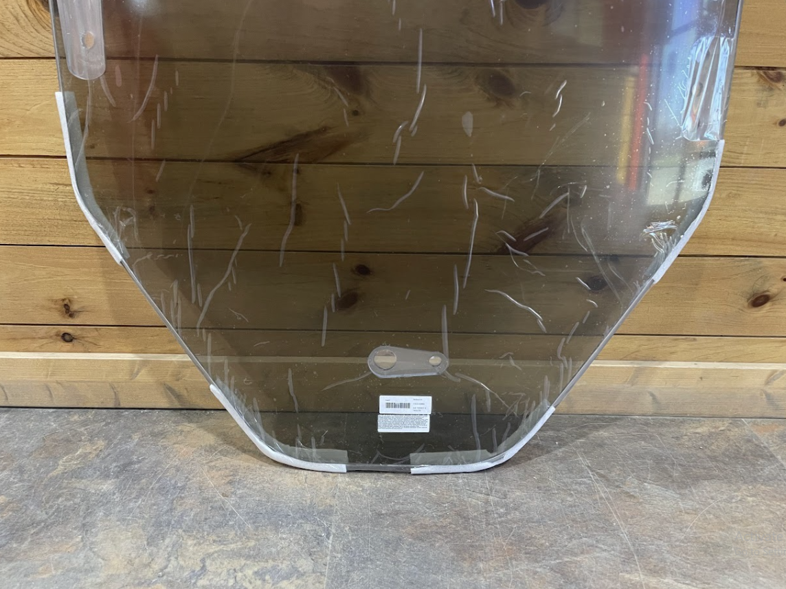 Close-up of Bobcat R Series polycarbonate windshield bottom corner showing rounded edge and product label