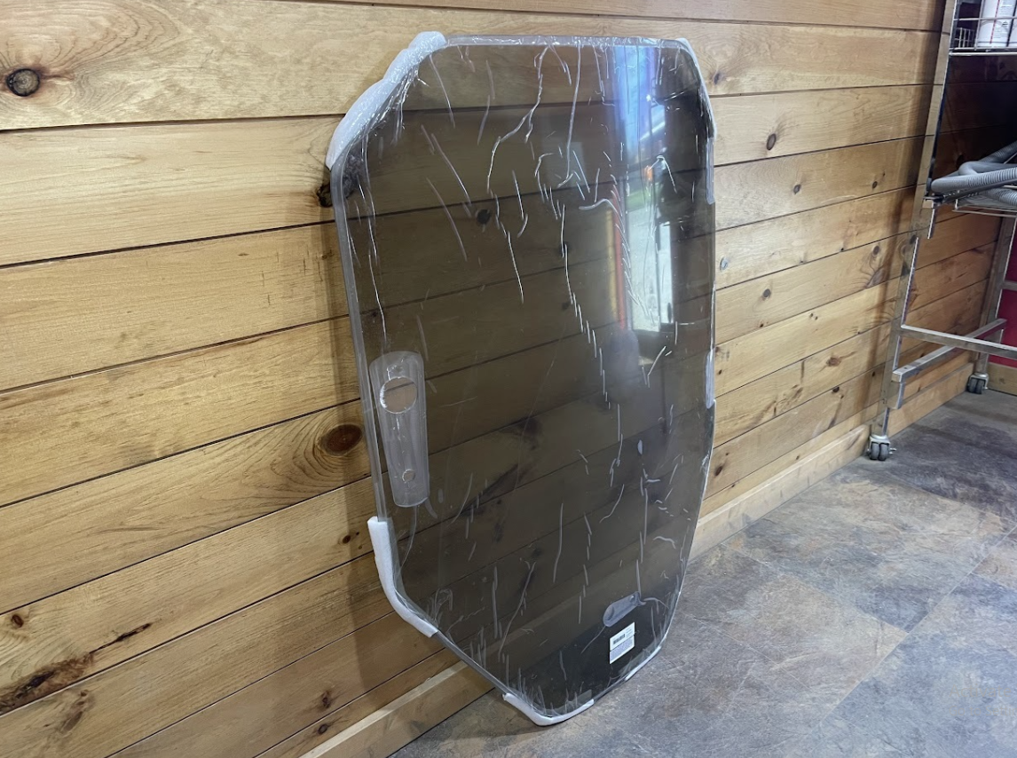 Tinted Bobcat R Series polycarbonate windshield replacement standing upright, showing full panel and mounting tabs