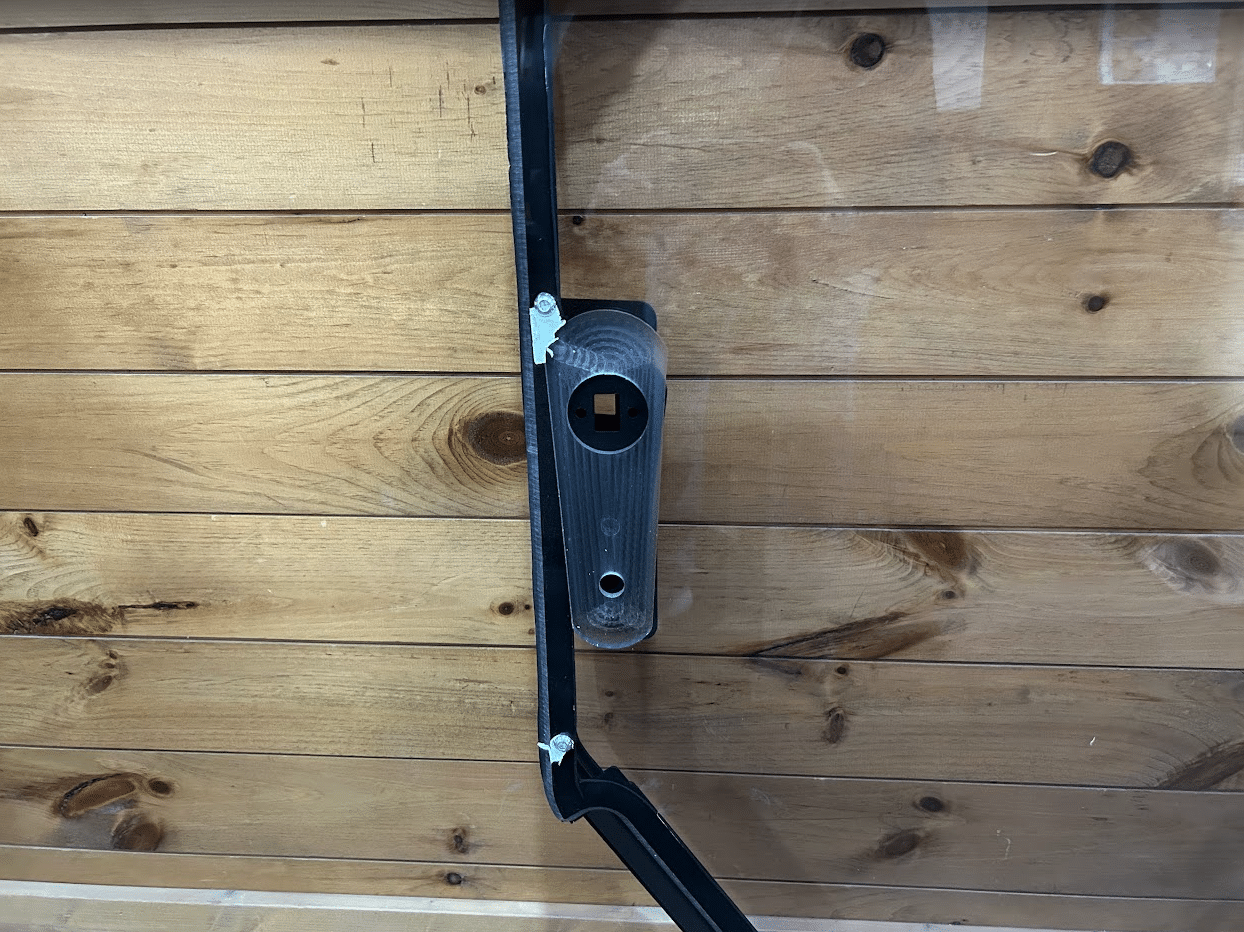Close-up detail of Bobcat S86 T86 windshield frame showing latch mechanism and frame corner