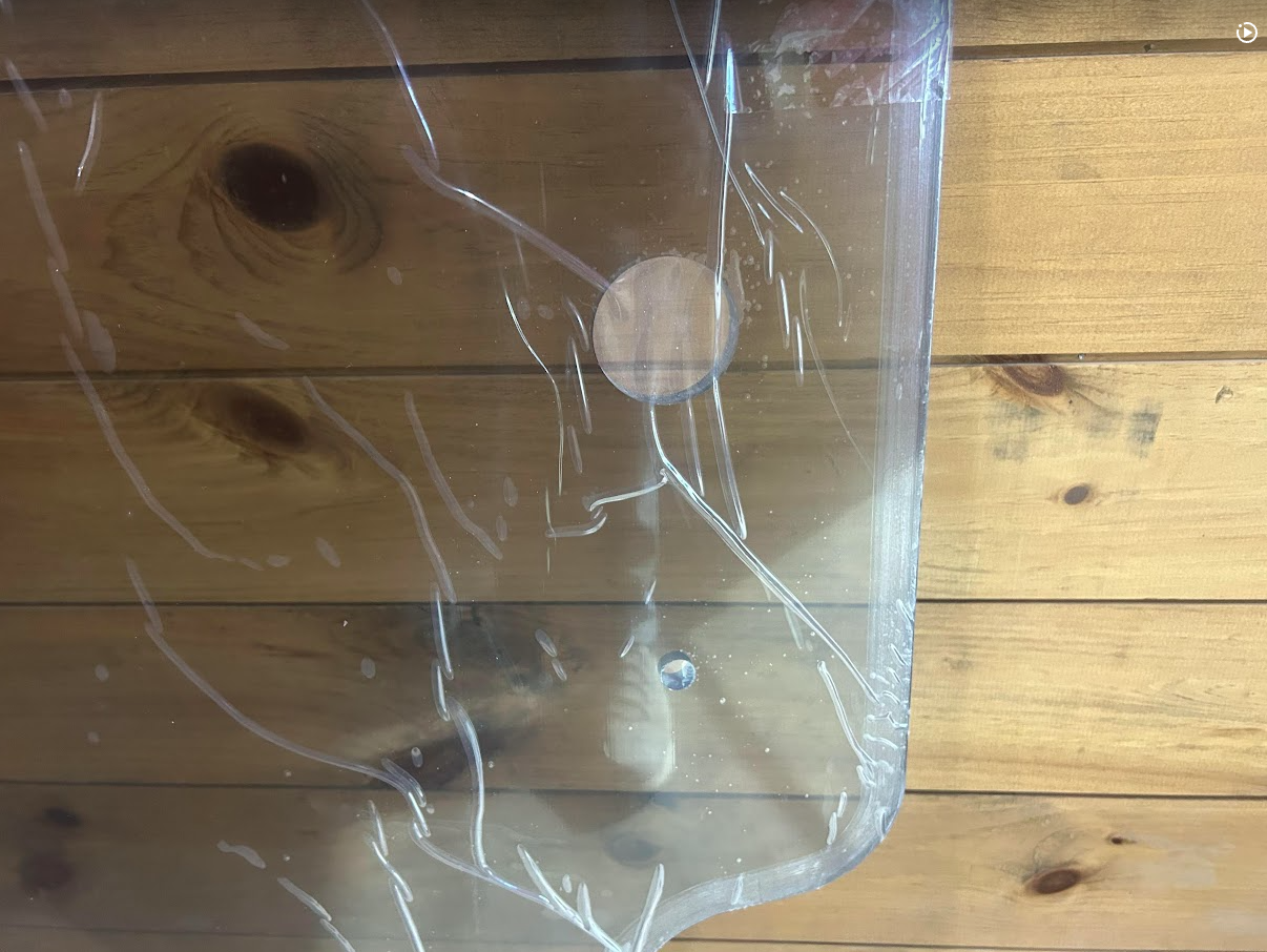 Close-up of Case SR TR SV TV Series clear polycarbonate windshield panel showing mounting grommet hole and milled edge detail