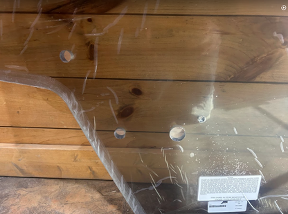 Close-up of Case SR TR SV TV Series clear polycarbonate windshield corner showing OEM mounting holes and product label with protective film
