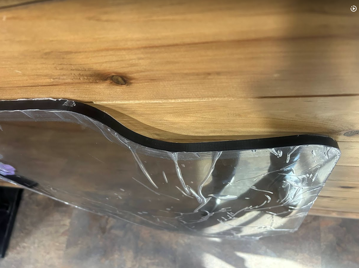 Close-up of Case SR TR SV TV Series polycarbonate windshield milled and polished edge showing panel thickness with protective film
