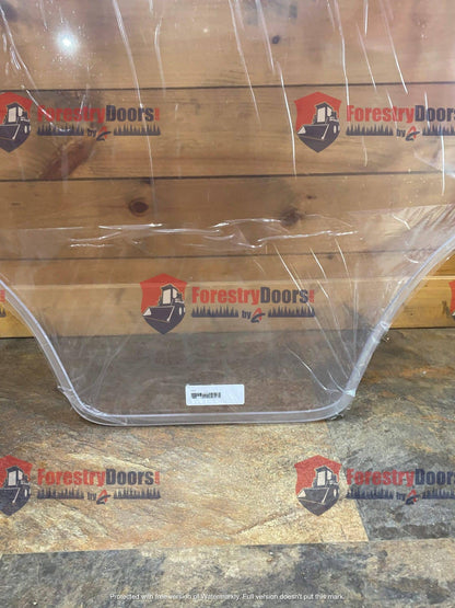 Bottom edge view of Caterpillar D Series clear polycarbonate windshield showing milled profile and protective film on wooden surface
