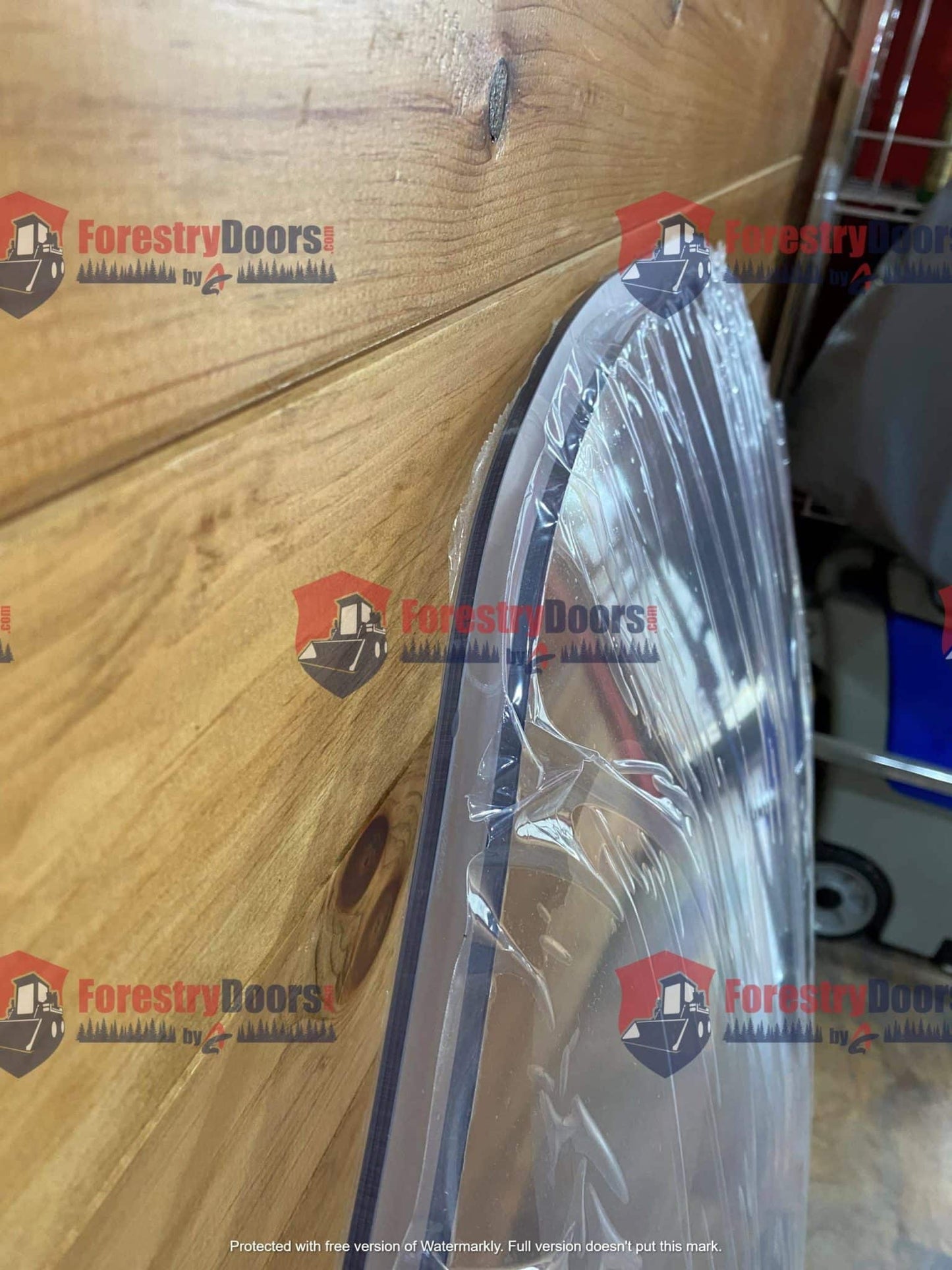 Close-up of Caterpillar D Series polycarbonate windshield curved upper edge with protective film on wooden background