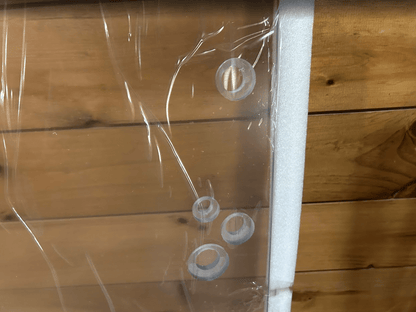 Close-up of multiple mounting holes along the edge of a clear polycarbonate skid steer windshield