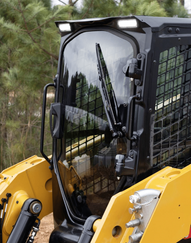 Yellow Caterpillar skid steer fitted with a clear polycarbonate replacement windshield, viewed from the front outdoors