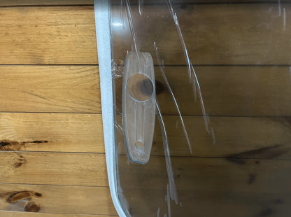 Close-up of a mounting hole on the edge of a tinted polycarbonate skid steer windshield