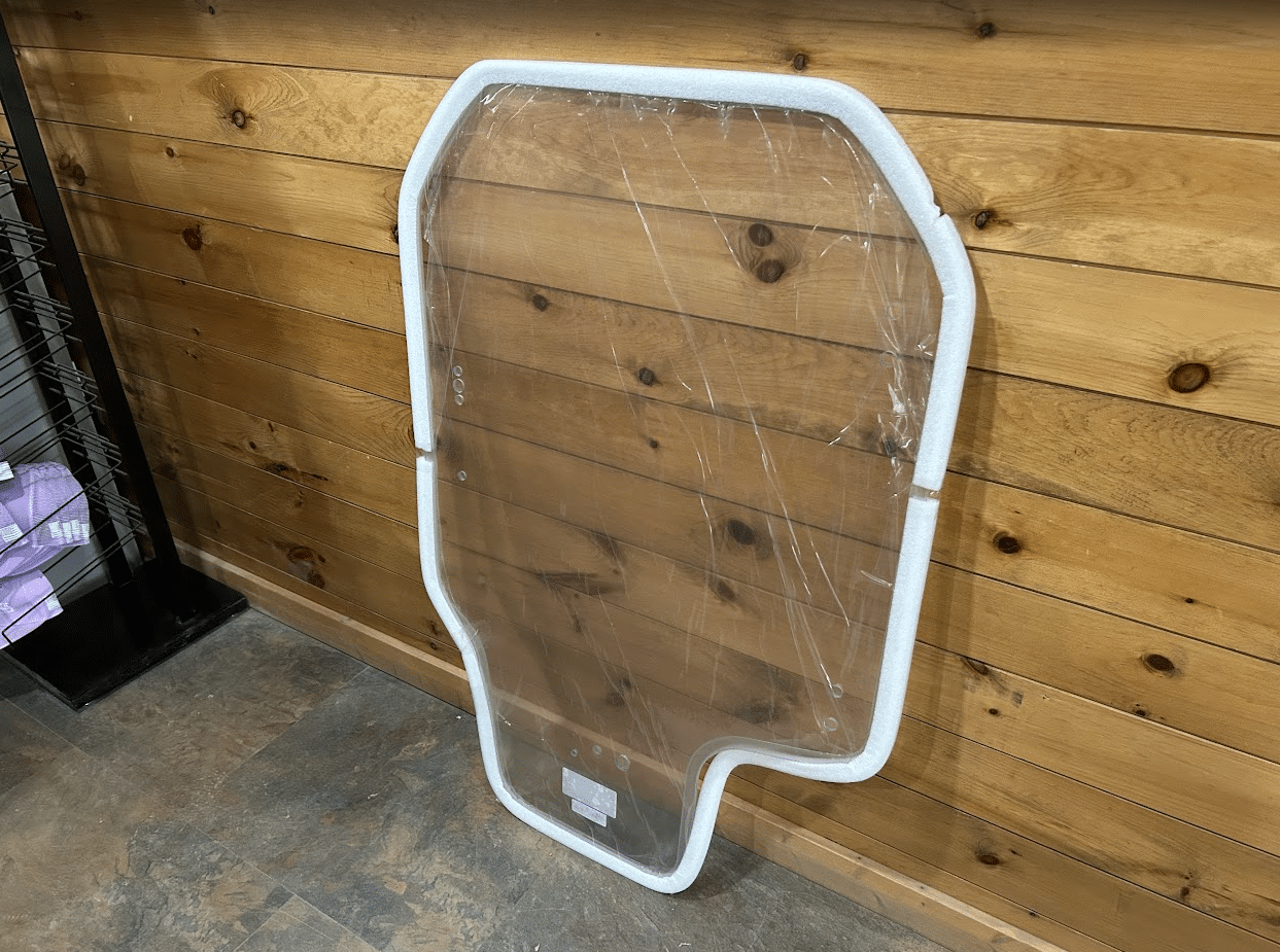 Gehl R and RT series clear polycarbonate windshield panel leaning against wood wall at an angle