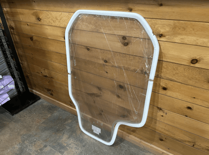 Gehl R and RT series clear polycarbonate windshield panel leaning against wood wall at an angle