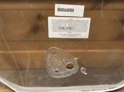 Back view of Gehl R & V Series polycarbonate windshield showing caution label, barcode, and OEM mounting bracket