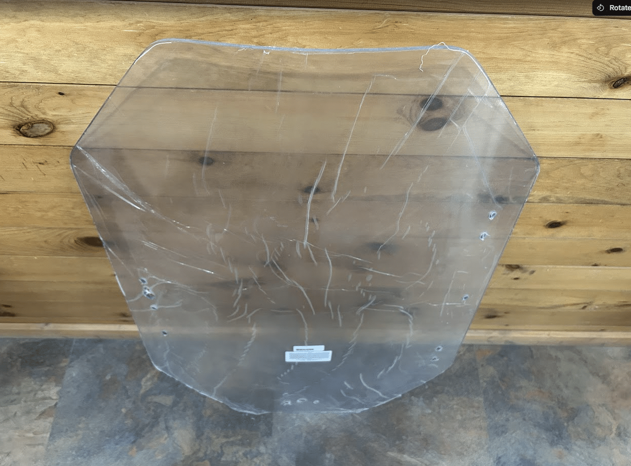 Gehl R & V Series clear polycarbonate windshield panel showing distinctive trapezoidal shape, overhead view