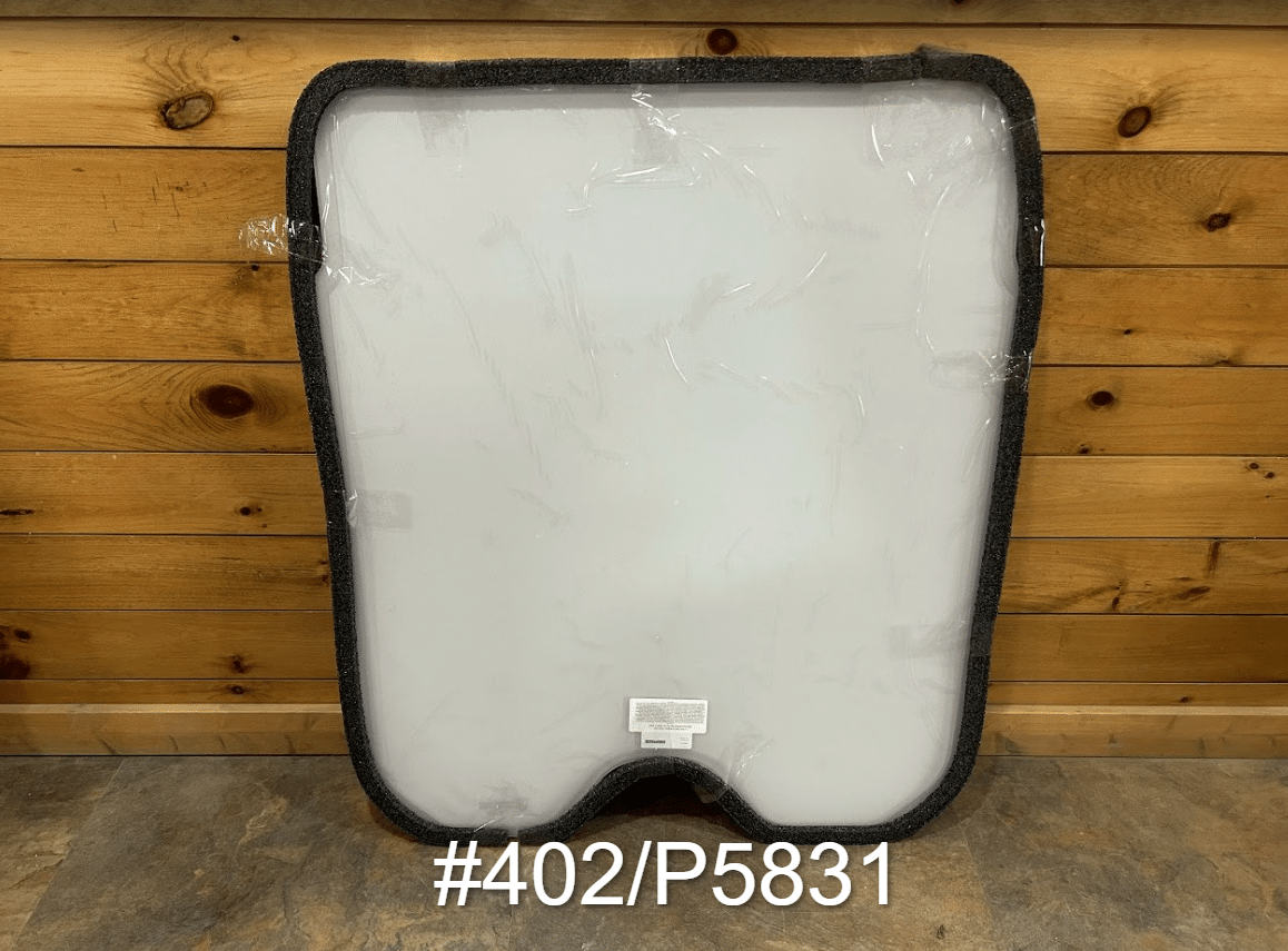 JCB #402/P5831 polycarbonate skid steer front windshield with rubber seal frame, shown in protective wrap against wooden wall