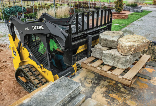John Deere 317G compact track loader on a job site moving large stones