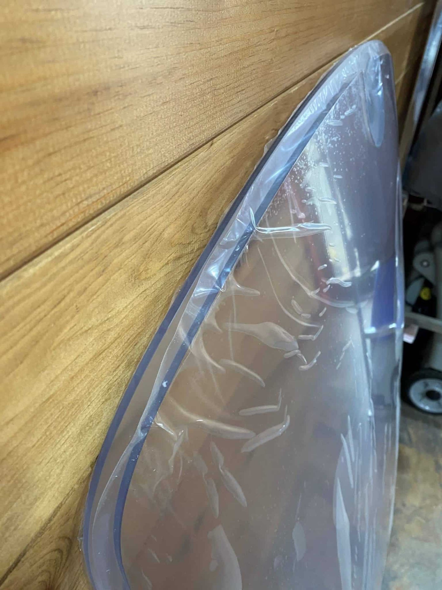 Close-up side edge view of John Deere D Series polycarbonate windshield showing material thickness and curvature