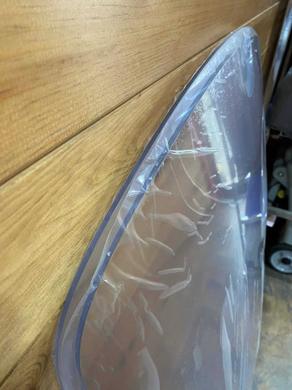 Close-up side edge view of John Deere D Series polycarbonate windshield showing material thickness and curvature