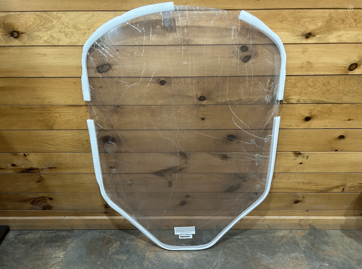 John Deere G Series small frame clear polycarbonate windshield with white frame, full front view against wooden background