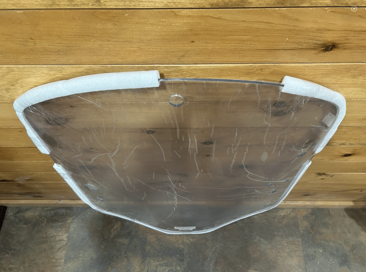 Bottom edge view of John Deere G Series small frame clear polycarbonate windshield with foam corner protectors