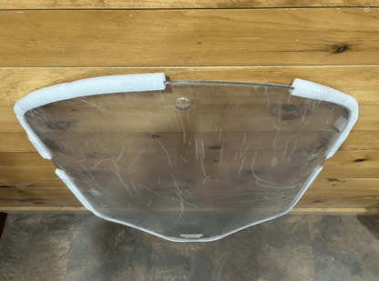 Bottom edge view of John Deere G Series small frame clear polycarbonate windshield with foam corner protectors