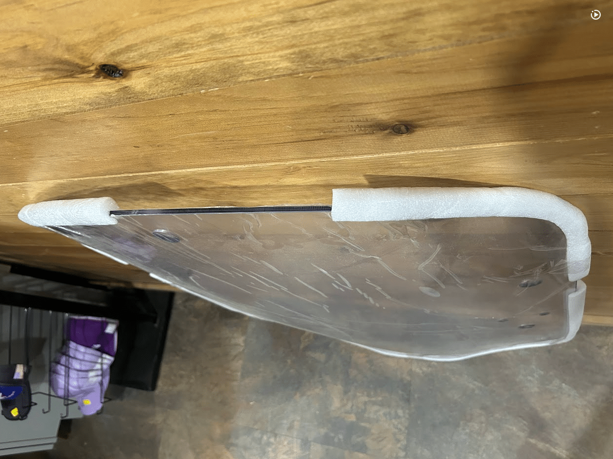 Edge-on view of John Deere G Series small frame polycarbonate windshield top curve showing foam edge protectors