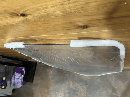 Edge-on view of John Deere G Series small frame polycarbonate windshield top curve showing foam edge protectors