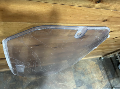 Close-up of John Deere P Series windshield upper corner showing mount tab and edge profile
